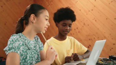 Afrika 'lı bir erkek ve beyaz bir kızın günlük giysiler içinde BTMM teknoloji sınıfında dizüstü bilgisayar ve elektronik ekipmanlarla kod yazma ya da programlama sisteminde birlikte çalıştıklarını gösteren site görüntüsü. Öğretim