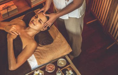 Beyaz kadın stres önleyici kafa masajı yapmaktan ve lüks otel veya otelde sıcak mum ışığında yüz güzelliği eğlencesi yapmaktan zevk alıyor. Sessiz.