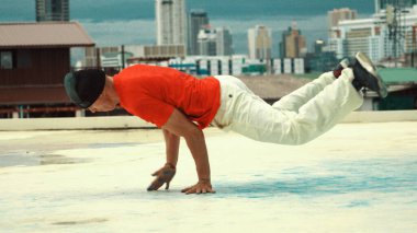 Beyaz hipster yüksek binanın çatısında B-boy performansı sergiliyor. Şehir veya şehir manzaralı çatıda break dans yapan genç bir profesyonel. Açık hava sporu 2024. Hiphop.