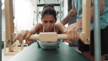 Pilates Cadillac masasında bar tabanlı bir alıştırmada bir müşteriye yardım eden eğitmen. Cadillac 'ta kuğu dalışı yapan kadın beden gücünü ve beden eğitimini arttırıyor. Alışkanlık.