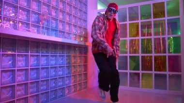 Yakışıklı, beyaz tenli sanatçı kurşun ışıkla dans etmek için dans ediyor. Güneş gözlüklü, şapkalı çılgın hippi dans ediyor ve modern gece kulübünde serbest dans dinlemenin tadını çıkarıyor. Mutluluk.