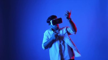 VR gözlüklü oyuncu sanal dünyaya girerken silah tutuşu yapıyor ve atış oyunu oynuyor. Mavi arka planda dururken simülasyon dünyasında zırh tutan yetenekli bir adam. Aygıt.