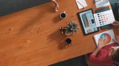 Renk paletinden renk seçmek için birlikte çalışan iş adamlarının üst düzey hava görüşü. İşadamı logo grafiğine bakarken pazarlama ekibine tablet kullanarak yönetici fikri sundu. Sempozyum.