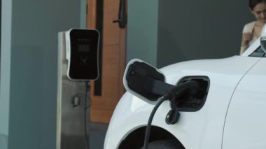 İlerici ebeveynler kızlarını okuldan alırken elektrikli araba ve yenilenebilir enerji kavramını kullandılar, evdeki EV otomobil için şarj istasyonu. Alternatif eko taşımacılığı.