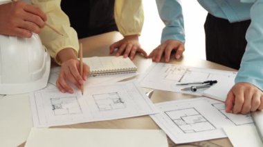 Mimari döküman, ölçüm araçları ve ahşap blokların modern ofiste etrafa saçıldığı masa üzerine planlar yapma konusunda akıllı mimar ve güvenlik mühendisi tartışması. - Yakın çekim. Tanımlama.