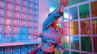 Çekici Asyalı sanatçı parlak neon ışıkta adım atıyor. Kameraya özgüvenle bakarken serbest stil müzikle dans eden yakışıklı break dans. Profesyonel hippi rahatla. Mutluluk.