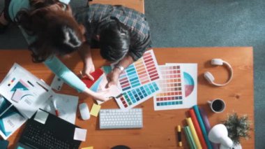 Akıllı tasarımcının renkli paletlerden renk seçmesine yardım ederken yukarıdan aşağı görünümü. Dizüstü bilgisayardan logoya bakarken birlikte çalışan ve planlayan iş adamlarının hava görüntüsü. Sempozyum.