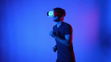 Meta evren egzersizi yaparken VR gözlüğü takan beyaz bir adam. Sanal gerçeklik ya da gelişmiş gerçeklik teknolojisi kullanarak atlet koşuyor. Spor konsepti. Eğlence için. Aygıt.