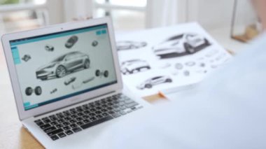 Araba tasarım mühendisi otomobil işi için otomobil prototipini ev ofisinde analiz ediyor. Otomotiv mühendisliği tasarımcısı dikkatle analiz eder, kusurları bulur ve dizüstü bilgisayarla araba tasarımında gelişmeler kaydeder.