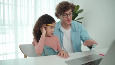 Baba, Amerikalı kız ekrana bakarken yapay zeka üretmeyi açıkla. Çekici beyaz bir baba, kızına kulaklıklı masada kod mühendisliği öğretiyor. Pedagoji.