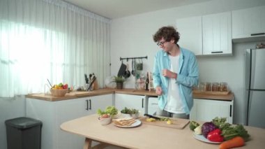 Mutlu baba yemek pişirirken müziğe geçiyor ve modern mutfakta öğle yemeği hazırlıyor. Aktif baba, sebze ve mutfak gereçleri ile çevrili sağlıklı yemek ya da salata yaparken şarkıyla dans ediyor. Pedagoji.