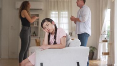 Sinirli ve mutsuz genç bir kız oturma odasında ebeveyninin tartışması yüzünden gerginliğin ortasında kanepede oturuyor. Sağlıksız ev hayatı ve travmatik çocukluk depresyona dönüşür.