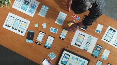 Ux Ui tasarımı üzerinde çalışan yazılım geliştiricisinin en üst görüntüsü. Ekip birlikte çalışarak yaratıcı dijital şirkette wirefram prototipi tasarlıyor. Takım çalışması konsepti. Cemaat.