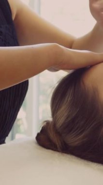 Lüks bir spa merkezinde masaj terapisti tarafından yüz masajı ve spa tedavisi için kaplıcaya uzanmış rahat bir kadın. Sağlık, stres atma ve gençleştirme kavramı.