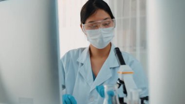 Laboratuvar kimya araştırmacısı mikroskop ve dizüstü bilgisayar kullanarak yeni ilaç ya da tedavi geliştirir. Bilimsel uzmanlığa ve laboratuvar mikrobiyoloji ekipmanlarına sahip sağlık teknolojisi. Ağır çekim. Katı.