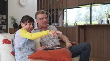 Grandfather and granddaughter eat french fries watch interesting entertainment on TV. Senior use technology communicate with young generation cross generation gap strengthen family bond. Divergence.