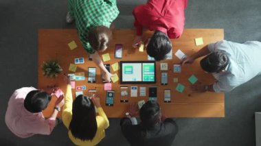 Ux ui tasarımını renkli yapışkan nota üzerine yazmak için birlikte çalışan geliştirici ekibinin üst görüşü. Tablet 'te kablo prototipi inceleyen ve yazılım tasarlayan bir grup programcı. Cemaat.