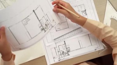 Ölçüm aracı ve kalem kullanan akıllı mimar ya da mühendisin videosu mimari ofisteki inşaat doğruluğu için bir el taslağı ayrıntılı taslağını karşılaştırıyor. Eline odaklan. - Yakın çekim. Tanımlama.