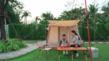 Aile hep birlikte bahçedeki kampta oturup yemek yiyor. Ebeveynler, genç nesil arasında iletişim kurmak ve zaman geçirmek için açık hava kamp faaliyetlerini kullanıyorlar. Uyumsuzluk.