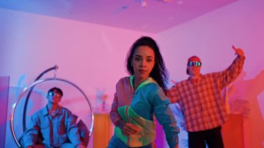 İspanyol hipster renkli kıyafetler giyer ve serbest stil müziğe el sallar. Profesyonel break dansçı neon ışıklarıyla ve modern stüdyo arkadaşlarıyla coşkuyla dans ediyor. Mutluluk.