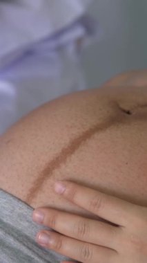 Mutlu hamile kadın, jinekolog doktoru hastanede ya da klinikte hamilelik danışmanlığı için ziyaret ediyor. Doktor, bebek ve anne sağlığı kontrolü için hamile karnı muayene ediyor. Jinekoloji konsepti.