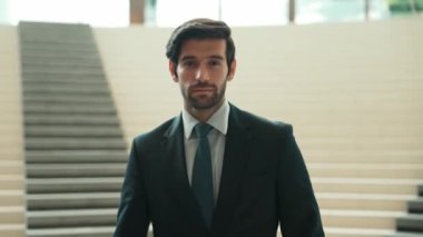 İş adamı kameraya bakarken kollarını kavuşturup arkasını dönüyor. Zeki, yakışıklı proje yöneticisi kameraya poz verirken kendine güvenen, arka planı bulanık bir şekilde merdivenlerde gülümsüyor. Sevinçli..