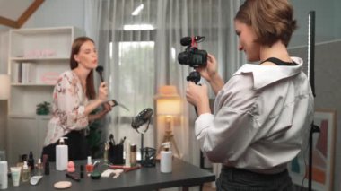 Etkilenen iki ortak canlı yayında video görüntülerini çekiyor makyaj malzemesi prim sosyal medya veya blog. Kozmetik stüdyosu ışıklandırmalı mutlu genç kız çevrimiçi pazarlama oturumu yayını için..