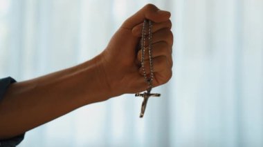 Hristiyan katolik takipçilerle dinsel bağlılık ve maneviyat duygusu doludur. Ağır çekimde el, güçlü bir kararlılıkla dini dua için kutsal haçı tutar. Filizlenen