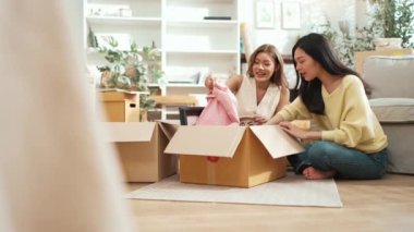 Oturma odasında karton kutuyla otururken konuşan ve oynayan mutlu lezbiyen sevgili. İki kız yeni eve taşınıyor ve birlikte konuşup yardım ediyorlar. Destekleyici kavram. Myrmidon.