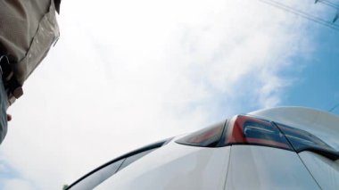 Dipte yavaş çekimde çalışan adam elektrik şebekesine bağlı EV araba aküsünü şarj ediyor. Elektrik endüstrisi çevre dostu araç için elektrik endüstrisi olarak çalışıyor. Yararlı