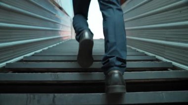 Merdivenlerden çıkan başarılı iş adamının bacağına yakın plan. Müdürün iş yerini değiştirmesi, yeni bir şey keşfetmesi, gelişmesi, terfi etmesi ya da gün ışığına çıkması. Yükseliyor. Bacağa odaklan. Sevinçli..