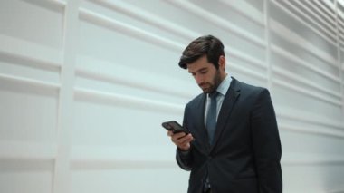 Yetenekli yönetici, iş arkadaşıyla proje hakkında konuşmak için telefon görüşmesi yapıyor. Yakışıklı erkek lider, ayakta durup kameraya bakarken satış hakkında konuşmak ve rapor vermek için iş ekibini arıyor. Sevinçli..