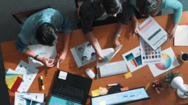 Takım ayakta dikilirken ve yorum yaparken müdürün fikir yazma konusunda üst düzey görüşü. Profesyonel tasarımcı logosu renk paletine bakarken ve renkli kalemle fikri kağıda yazarken. Sempozyum.