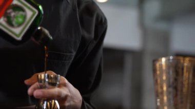 Karışık kokteyl barı hazırlamak için likör şekerini ölçmek için jigger tutan el barmenini yakından karıştırıyorum. Gece hayatı karışımı davetler veren özel bir içecek. Vinosity.