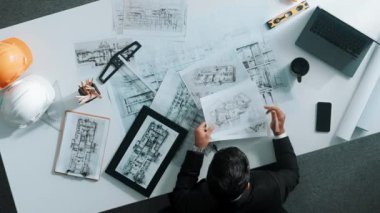 Tablet, dizüstü bilgisayar, güvenlik kaskı ve ekipmanlarla toplantı masasında otururken ev tasarımı için malzeme seçen yetenekli mühendis görüşü. Akıllı mimar proje planına bakıyor. Hizalama.
