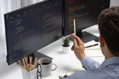 Bilgi teknolojisi geliştiricisi, bilgisayar ekranına bilgi doğrultuyor, program güncellemesi analizi yapıyor ve modern ofiste ilginç bir web sayfası verisi yaratıyor. Varsayım.