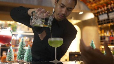 Bartender preparing to serve Midori sour with lime syrup pouring into saucer glass. Focusing special refresh japanese liqueur drink style showcasing nightlife mixology at nightclub luxury. Vinosity. clipart