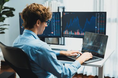 Piyasa stoku veri yatırımlarında dizüstü bilgisayara odaklanarak ekranlarda gerçek zamanlı dizüstü bilgisayar üzerinde çalışan genç bir tüccar. Modern ofiste, dinamik para bozdurma oranını analiz ediyorum. Toplayıcı.