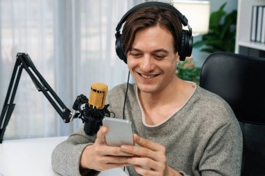 Akıllı yayıncının sunucu kanalı canlı sosyal medya yayını ile akıllı telefon kullanarak dinleyiciyle sohbet ediyor, kulaklık takarak modern ev stüdyosunda video kaydediyor. Bireysel.