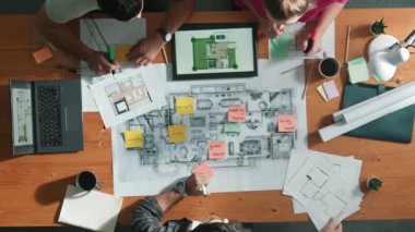 Bina planına bakarken inşaat mühendisinin elindeki belgelerin en alttaki görüntüsü. Mimarlık takımının fikir üretme ve planlama alanındaki hava görüşü masada planlı otururken. Sempozyum.