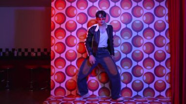 Asyalı break dansçı serbest stile geçiyor ve balon arka planlı kameraya bakıyor. Profesyonel hippi gündelik kıyafet giyer ve gözlük takar. Mutluluk.