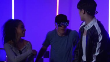 Gündelik gömlekli, gözlüklü, neon ışıkla dans eden farklı insanlar. Gece kulübünde dans ederken kameraya bakıp sokak dansı yapan çok kültürlü break dansçı. Mutluluk.