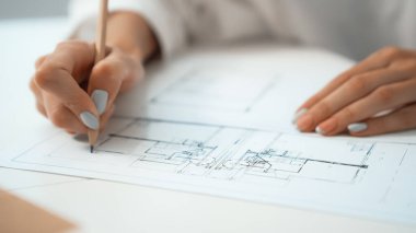 Profesyonel Kafkas kadın mühendis el çizimi taslağı yakın plan. Masaya yerleştirilmiş planlı ve mimari ekipmanlı yaratıcı tasarım ve takım çalışması konsepti. Eline odaklan. Tertemiz..