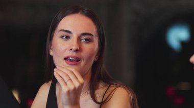 Lüks bir kokteyl barında grup arkadaşıyla konuşan güzel bir kadının portresi. Gece kulübünde sosyetik etkileşim için doğal yüz güzelliğini kostüm içinde yakalamak. Vinosity.