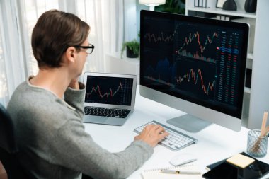 Bilgisayar ve dizüstü bilgisayarı kullanarak, çalışma masasındaki dinamik artırılmış borsa grafiğinin en yüksek kar değerini araştıran bir tüccar, modern ofisteki ekrandaki döviz kuru değerini analiz ediyor. Bireysel.