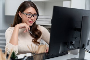 Gündelik kıyafet gülümseyen, gözlük takan güzel iş kadını bilgisayar hakkında rapor hazırlıyor, pazarlama planı hazırlıyor ve modern ofiste güncelleme promosyonuyla yeni müşteri hedefini analiz ediyor. Varsayım.