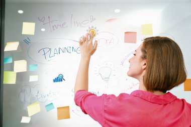 Genç ve güzel iş kadını, zihin haritası ve renkli yapışkan notla finansal sorunları çözerken cam panoya etiket yapıştırıyor. Yaratıcı iş konsepti. Tertemiz..