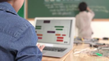 Kız, yazılım geliştirme planı yazarken yapay zeka yazılımı ya da programlama sistemini kullanarak kök sınıftaki elektronik ana tahtada yapay zeka üretiyor. Pedagoji.