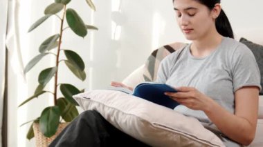 Kanepede oturan bir kadın ders kitabı okuyarak sosyal ve mesleki teknoloji bilgisini artırır ya da akıllı bir anne olmak için çocuk yetiştirir. Hayat boyu öğrenme konsepti. Uyumsuzluk.