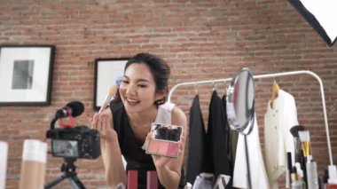 Kadın nüfuzlu kişi canlı yayın yapan video görüntülerini sosyal medya ya da blog üzerinden gözden geçiriyor. Kozmetik stüdyosu ışıklandırmalı mutlu genç kız çevrimiçi pazarlama oturumu yayını için..